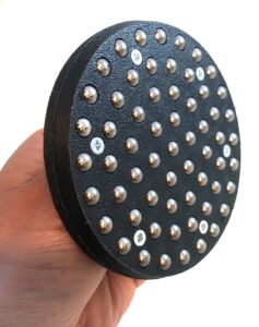 A hand holding a black ball bearing baren showing the underside