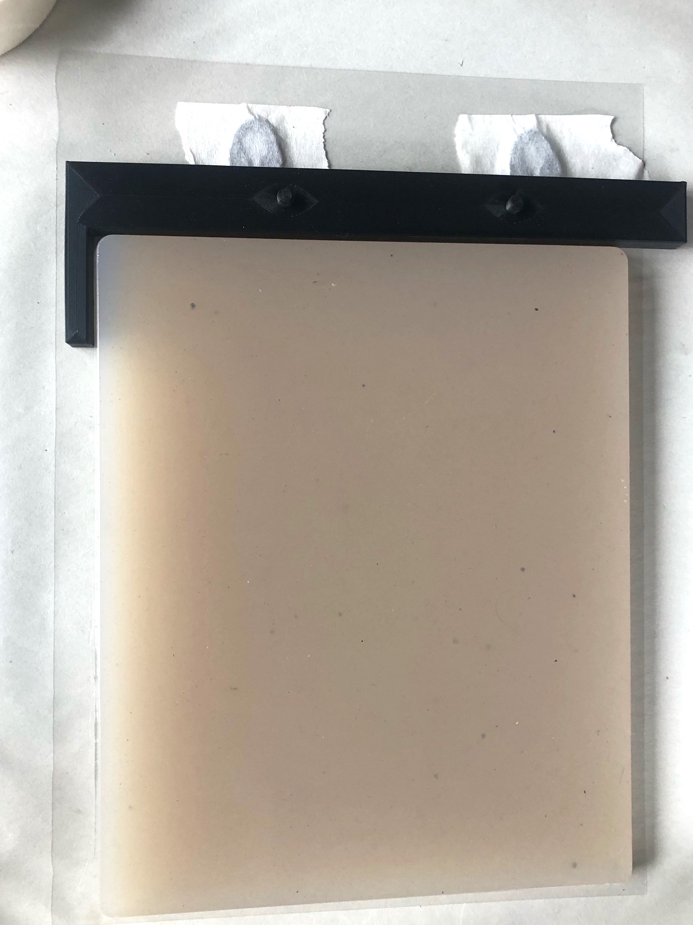 Black hole punch registration board, taped onto work surface, shown with homemade agar gel plate