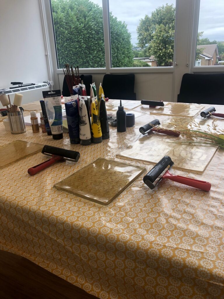 A gel printing workshop in a library, with tools and materials laid out on a table.